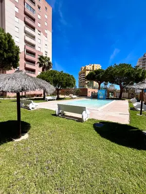 a swimming pool in a park with an umbrella at Apartamento en la Playa Canet, muy cerca de Valencia in Canet de Berenguer