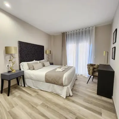 a bedroom with a large bed and a chair at MD Pont de Fusta in Valencia