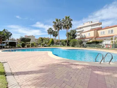 a swimming pool with palm trees and buildings at Global Vacacional, Planta Baja con Piscina en Canet de Berenguer in Canet de Berenguer