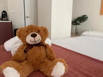 a brown teddy bear sitting on a bed at Osito Hub - Pintor Nicolau in Valencia