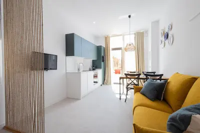a living room with a yellow couch and a kitchen at FLORIT FLATS - Stylish Studio by the Joaquin Sorolla Station in Valencia