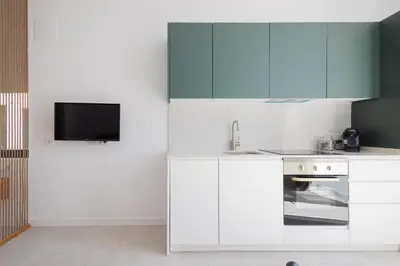 a kitchen with white cabinets and a flat screen tv at FLORIT FLATS - Stylish Studio by the Joaquin Sorolla Station in Valencia