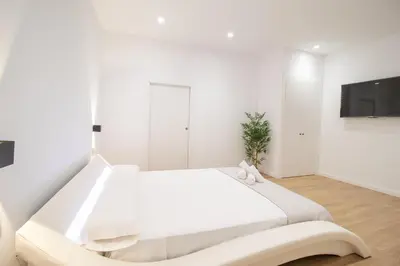 a white bedroom with a large bed and a flat screen tv at BedTime Suites by Concept Flats in Valencia
