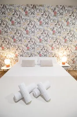 a bedroom with a white bed with a floral wallpaper at Suite Parque del Turia by Concept Flats in Valencia