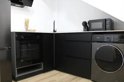 a black kitchen with a microwave and a dishwasher at Las Arenas Suites 2 Playa in Valencia