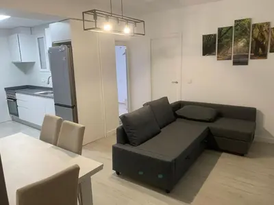 a living room with a black couch and a kitchen at Aerofira Paterna in Paterna