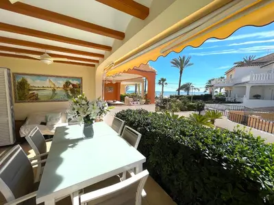 a patio with a table and chairs on a balcony at Bungalow on the beach 15 minutes from Valencia in Valencia