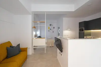 a living room with a yellow couch and a kitchen at FLORIT FLATS - Quiet and Cozy Studios by the Joaquin Sorolla Station in Valencia