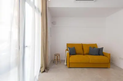 a yellow couch with two blue pillows in a room at FLORIT FLATS - Quiet and Cozy Studios by the Joaquin Sorolla Station in Valencia