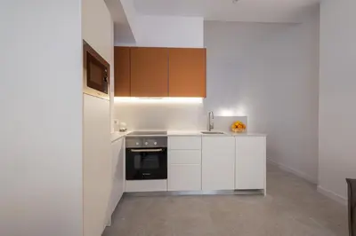 a kitchen with white cabinets and a black appliance at FLORIT FLATS - Quiet and Cozy Studios by the Joaquin Sorolla Station in Valencia