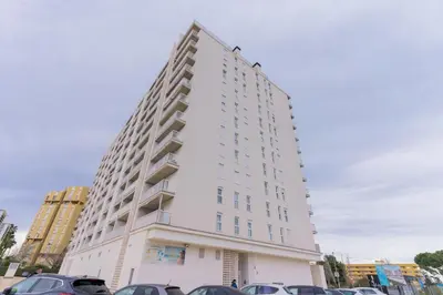a white building with cars parked in a parking lot at Canet Seaview Gem: Pool & Beach Proximity in Canet de Berenguer