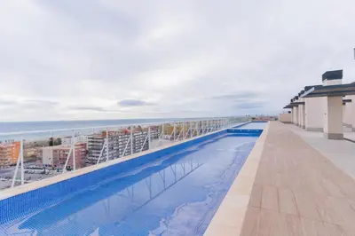 a swimming pool on the roof of a building with the ocean at Canet Seaview Gem: Pool & Beach Proximity in Canet de Berenguer