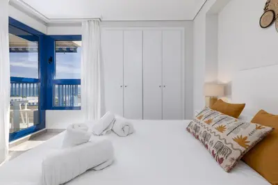 a white bedroom with a large bed and a window at ApartUP Patacona Infinity in Valencia