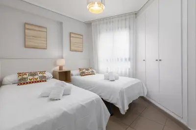 two beds in a room with white walls at ApartUP Patacona Infinity in Valencia