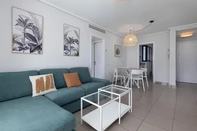 a living room with a blue couch and a table at ApartUP Patacona Infinity in Valencia