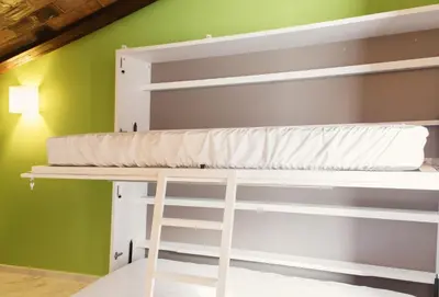 a bunk bed with a ladder in a room with a green wall at Ad Hoc Carmen in Valencia
