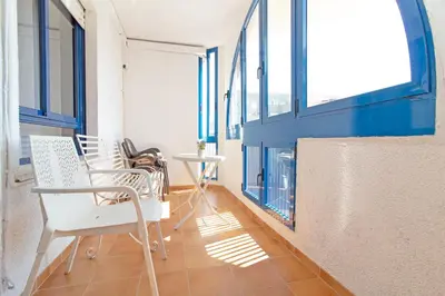a room with two chairs and a table and windows at Global Vacacional, Apartamento cerca de la playa en Puerto Sagunto in Puerto de Sagunto