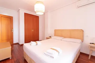 a bedroom with a large white bed with two towels at Global Vacacional, Apartamento cerca de la playa en Puerto Sagunto in Puerto de Sagunto