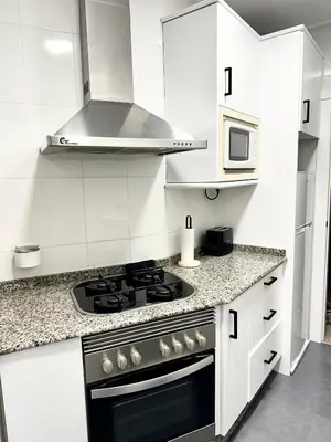 a white kitchen with a stove and a microwave at Casa Únic - Modern Central Home in Ruzafa in Valencia