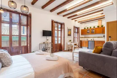 a bedroom with a bed and a couch and a kitchen at Sunny Modern Flat by Mercado Central in Valencia