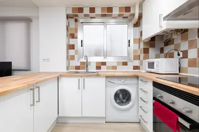 a kitchen with white cabinets and a washing machine at Barraca Breeze in Valencia