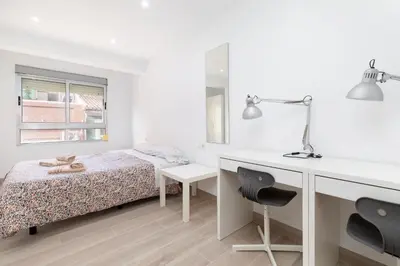 a white bedroom with a bed and a desk at Barraca Breeze in Valencia