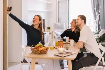 a group of people sitting around a table with their arms in the air at Coliving La Alfareria in Valencia