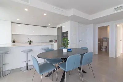 a kitchen and dining room with a table and blue chairs at Global Vacacional, Nuevo apartamento con piscina privada y terraza con vistas al mar in Canet de Berenguer