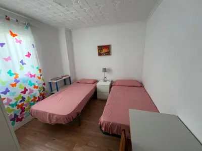 a room with two beds and a window in it at Piso a 3 minutos de la playa!! 6 personas in Cullera