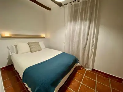 a bedroom with a bed with a blue blanket and a window at Apartamentos Ca Federo, Casa la Tía Elena in Losa del Obispo