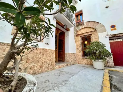 a building with a tree in front of a door at Apartamentos Ca Federo, Casa la Tía Elena in Losa del Obispo