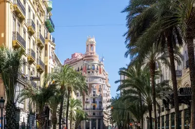 a tall building with a clock tower behind palm trees at Relaxing Reina in Valencia