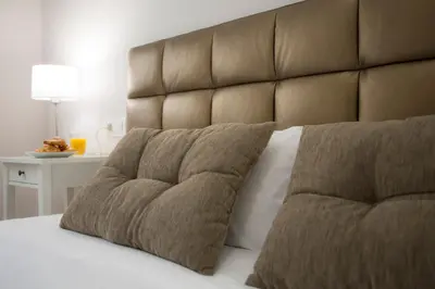 a bed with a large brown headboard and two pillows at SingularStays Comedias in Valencia