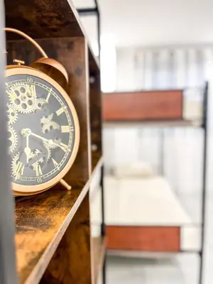 a clock sitting on a shelf next to a bed at Diyenn Burriana alojamiento y placer in Burriana