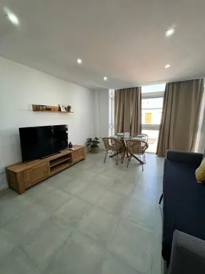 a living room with a flat screen tv and a table at UIM Mediterraneo PB Cendoya 1 wifi in Puerto de Sagunto
