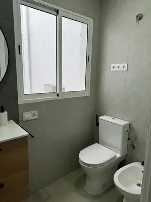 a bathroom with a toilet and a sink and a window at UIM Mediterraneo PB Cendoya 1 wifi in Puerto de Sagunto