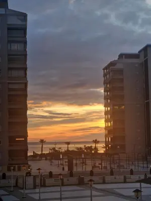 a sunset in a city with buildings and palm trees at Relájate en pareja o familia!!! in Tavernes de Valldigna