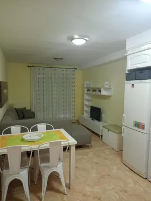 a kitchen and living room with a table and a refrigerator at Relájate en pareja o familia!!! in Tavernes de Valldigna