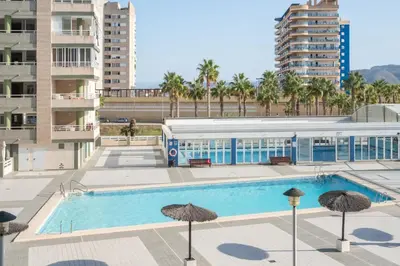 a swimming pool with umbrellas in front of a building at Relájate en pareja o familia!!! in Tavernes de Valldigna