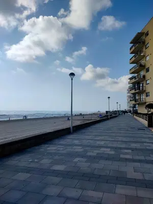a boardwalk on a beach with a building and the ocean at Modern Apartment Frontline Beach in Mareny Blau
