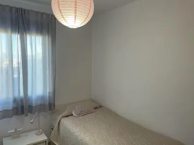 a small bedroom with a bed and a window at Excelente ático con gran terraza y barbacoa en Canet d'en Berenguer in Valencia