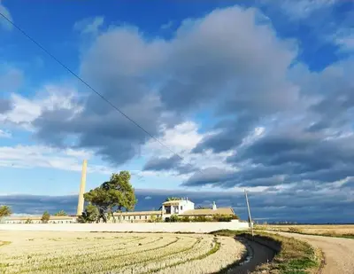 a dirt road in front of a field with a building at Hotel Rural El Teular in Sueca