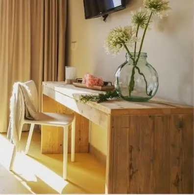a vase with flowers sitting on a wooden table at Hotel Rural El Teular in Sueca