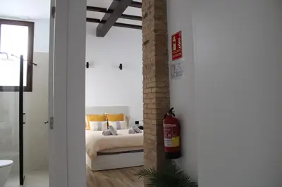 a bed with grey blankets and pillows on it at Las Arenas Suites 1 PLAYA in Valencia