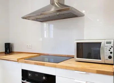 a white kitchen with a microwave and a stove at Mar de fonts ain in Ahín