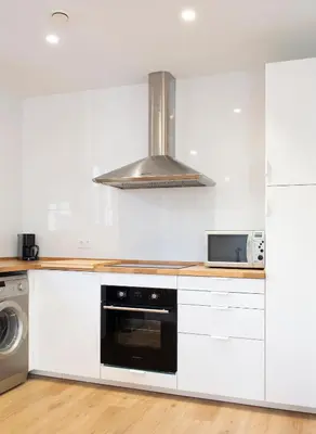 a kitchen with white cabinets and a stove top oven at Mar de fonts ain in Ahín