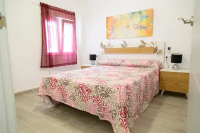 a bedroom with a bed with a red and white bedspread at El hogar del mar. in Sueca