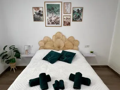 a bedroom with a white bed with green pillows at Bonita Planta baja con patio en 1ª línea de playa in Puerto de Sagunto