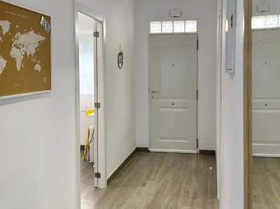 a hallway with white walls and a door and wooden floors at Bonita Planta baja con patio en 1ª línea de playa in Puerto de Sagunto