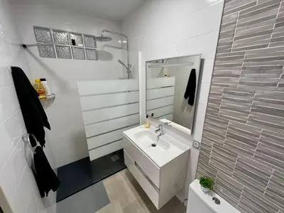 a white bathroom with a sink and a mirror at Bonita Planta baja con patio en 1ª línea de playa in Puerto de Sagunto